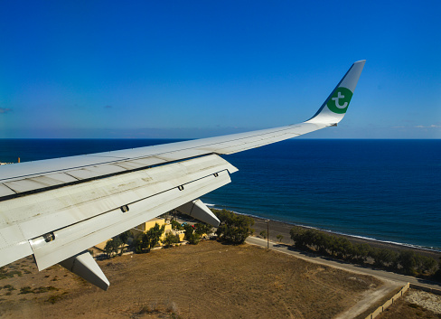 Santorini, Greece - Oct 8, 2018. Aerial view from window and wing of Boeing 737-800 airplane of Transavia on a cloudless day.