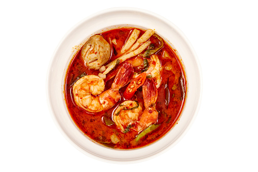 Top view of Creamy Tom Yum Kung Soup, That is a very popular dish in Thailand, containing of vegetables and herbs such as chili, lemongrass, lime leaves, lime and mushrooms.