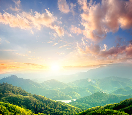 Sunrise over green forest with mountains and river background