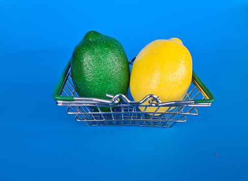 Lemon in a basket, shopping trolley on a blue background. Buying fruit