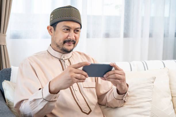 istock Happy young Asian Muslim man using a mobile phone at home 1469392406