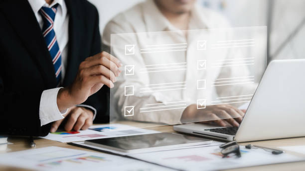 istock Businessman concept evaluating smart checklist on virtual screen. Business man using a pen to make accurate marks about topic survey in digital form modern office 1469393366