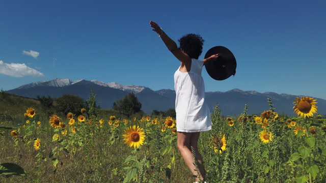 Summer girl happy in sunflower flower field run, jump, rotate in slow motion with arms raised up
