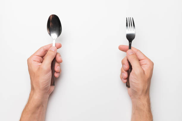 istock male hands hold a fork and a spoon without a plate on a white background, hunger, waiting for food 1469401117