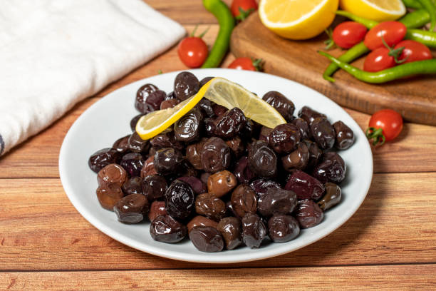 Black olive. Fermented olives and lemon slice in plate. Mediterranean flavors stock photo