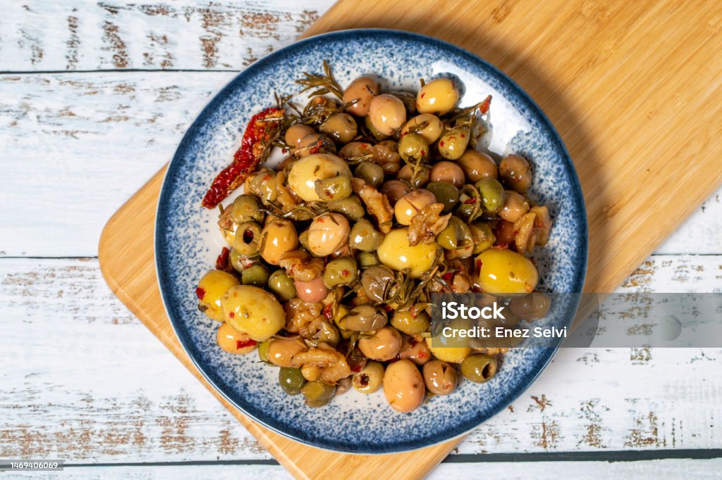 Mixed green olives. Green olive salad on wood background. Mediterranean flavors. Top view Marinated Stock Photo