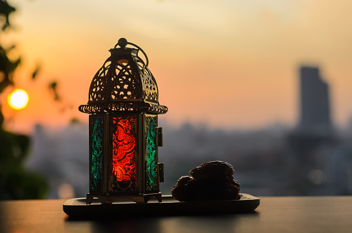 Lantern and dates fruit with dusk sky and city background for the Muslim feast of the holy month of Ramadan Kareem.