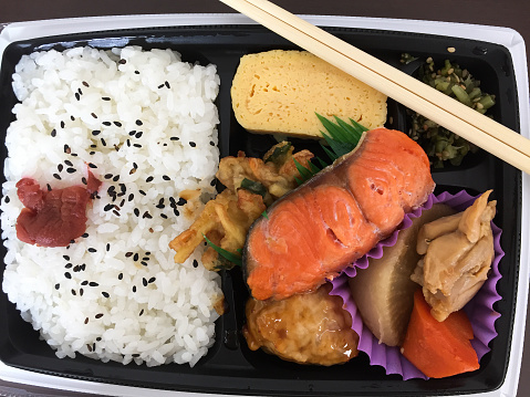 Japanese Bento box with rice, vegetables, chicken and salmon fish.