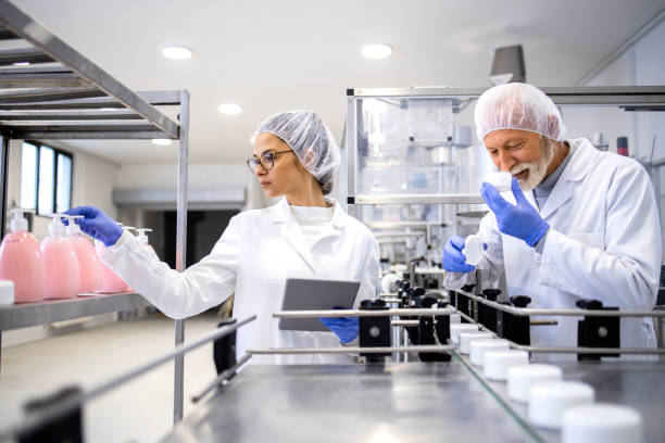 istock Production line workers standing by conveyor machine and controlling manufacturing of cosmetics products for pharmaceutical industry. 1469432897