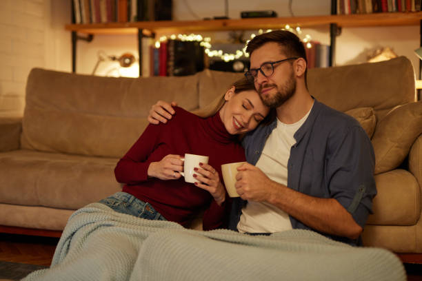 istock Young couple drinking tea while sitting in the living room at night 1469442018