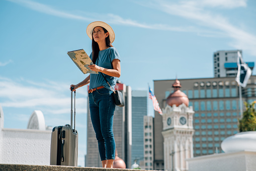 Cheerful Asian female traveler using a map in the city