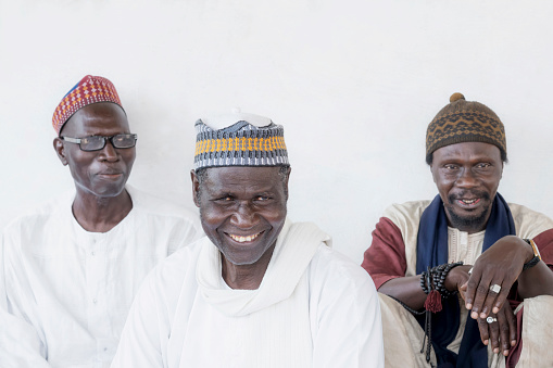 Thiaroye, Dakar, Senegal, Africa – September 3, 2021: Three Muslim men, a Friday in Senegal. Unidentified old Muslim men waiting for the opening of the mosque, celebration clothing
