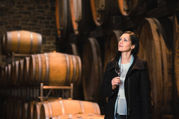 Woman tasting wine at the wine cellar Woman tasting wine at the wine cellar with barrels in background wine producer stock pictures, royalty-free photos & images