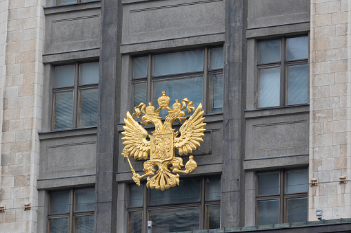 Golden coat of arms of Russia on the facade State Duma building at Moscow city, Russia. Double headed eagle is a national emblem of Russia