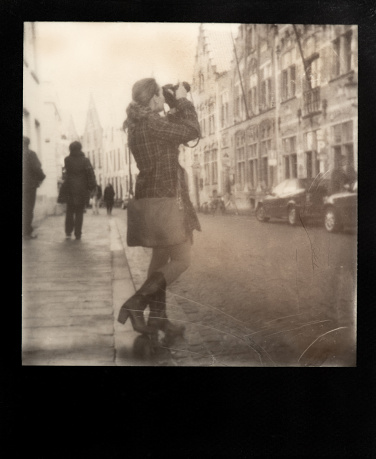 Traveller on a city street makes a photo of sightseeings.  Polaroid photo.