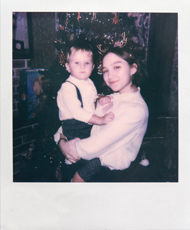 Boy and girl celebrating Christmas indoors.  Polaroid photo.