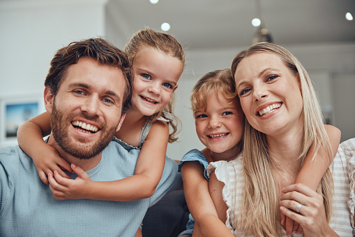 Family, happy portrait and relax together in home for quality time, relationship bonding and support in family home. Love, care and children hugging parents for happiness or smile in living room