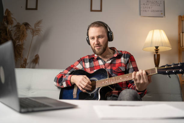 istock 40s man learning the guitar using laptop with online lessons at home. 1469457232