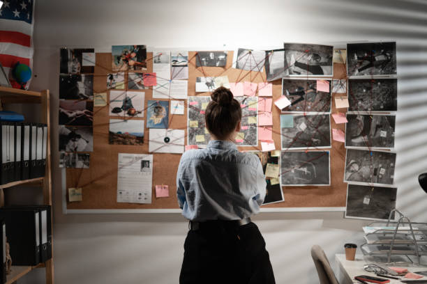 istock Young female detective looking at evidence board, back view. 1469457631