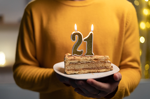 istock Cake with the number 21 lighted candles in men hands. 21th birthday 1469458245