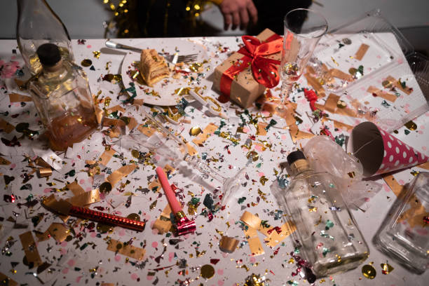 istock Confetti, empty bottles and party hats on a white table. After party concept 1469458584