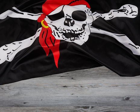 Skull and Crossbones of the black Pirates Flag aka the Jolly Roger with a wooden background and copy space