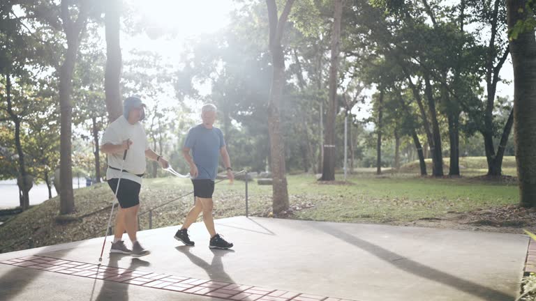 Asian Chinese Guide runner and visually impaired mature man walking up staircase in the park during weekend morning