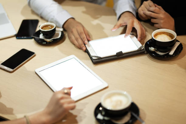 Colleagues having a business meeting at a cafe. Drinking coffee and working on laptop and tablet. stock photo