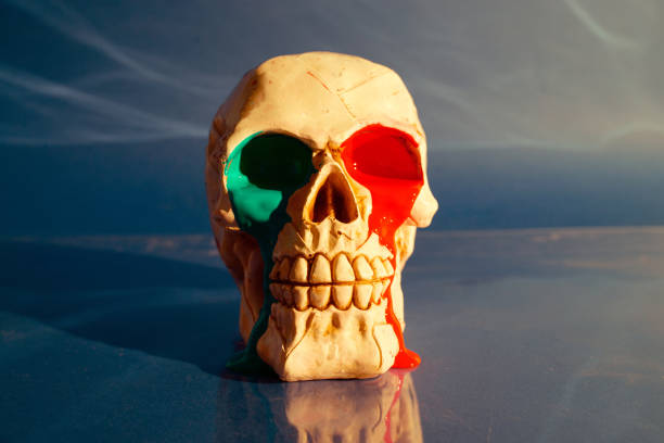 Skull with red and green paint leaking from eyes on blue background.