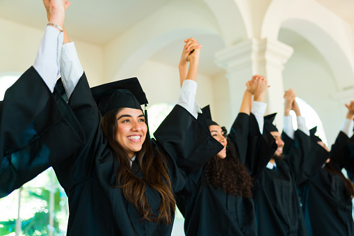 Latin gorgeous woman celebrating with graduates at campus during their graduation ceremony