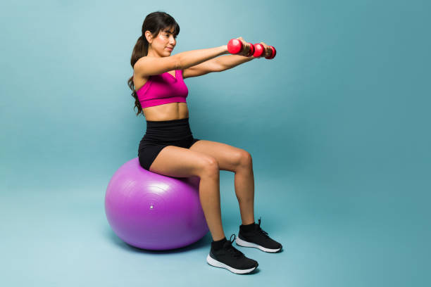 istock Active latin woman training with a stability ball and weights 1469476883