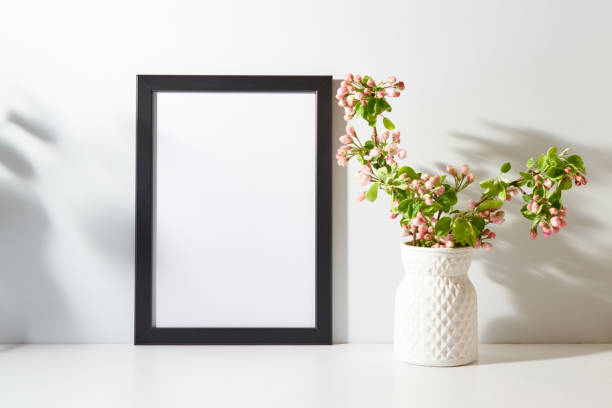 istock Mockup with a black frame and spring flowers in a vase on a light background. Empty poster frame mockup for presentation design, text, lettering 1469481099