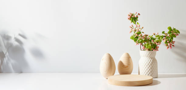 istock Empty round wooden podium for product presentation. Spring flowers in a vase and easter eggs on a light background. 1469481102