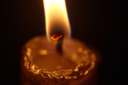 Closeup of burning candle isolated on black background. Melted Wax Candles Burning at Night.