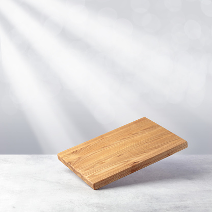 Cutting board falling on a grey stone table. Culinary background. Empty wooden cutting board, product display space.
