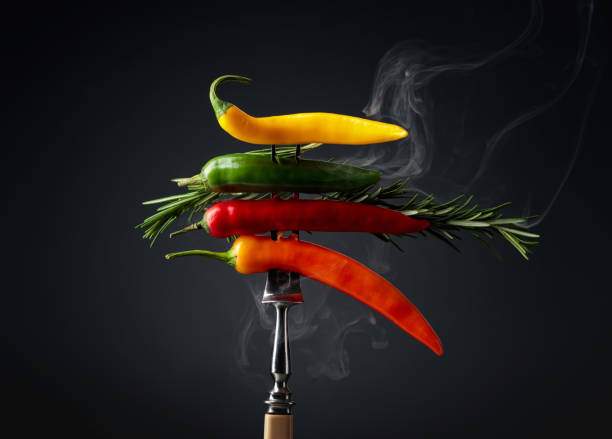 Hot chili peppers with rosemary on black background. Concept of spicy food.