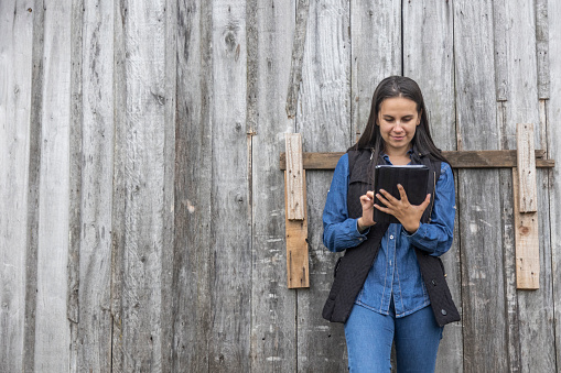 woman using tablet on wooden farm wall
