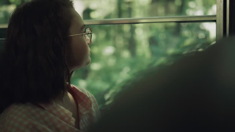 School girl sitting bus alone close up. Teen brunette looking window on greenery