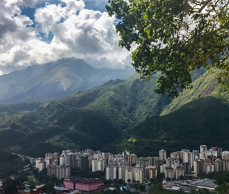 High angle view of Caracas city with green mountains. Buildings in valley with large mountain range.