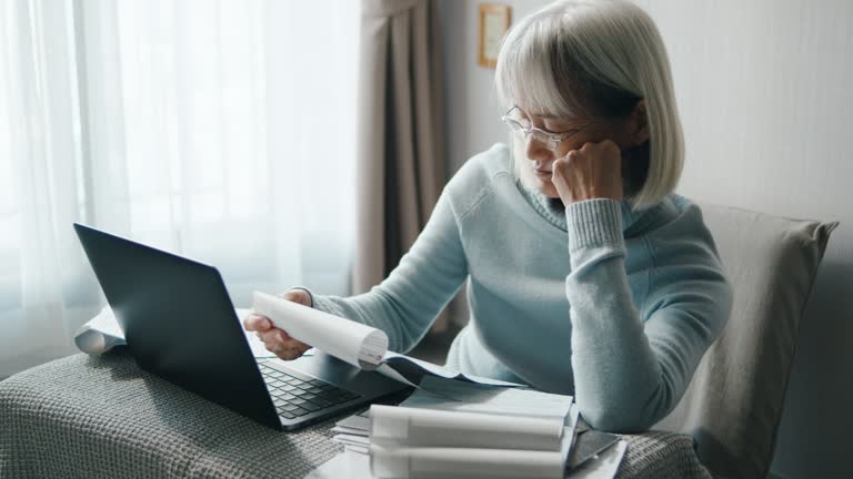 Stressed senior woman looking at all financial bills