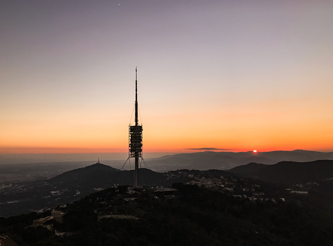 View of Collserola Tower on Tibidabo mountain during sunset. Television tower antenna over a mountain in Barcelona, Spain