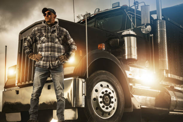 Professional Truck Driver Proudly Standing in Front of His Heavy Duty Vehicle stock photo