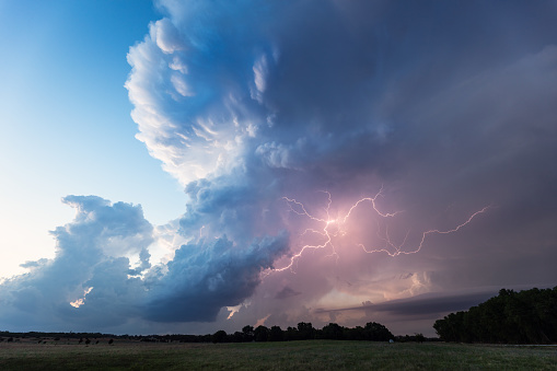 A dramatic thunderstorm cumulonimbus cloud illuminated by lightning over a field in Oklahoma.