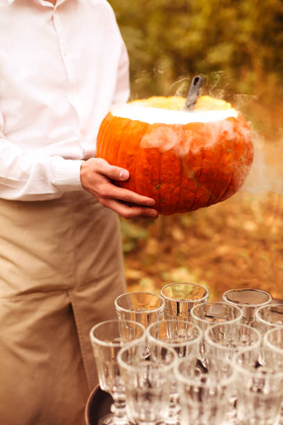 Crop man holding Halloween punch High angle of anonymousmale with punch near pumpkin bowl during Halloween celebration crystal chalice stock pictures, royalty-free photos & images