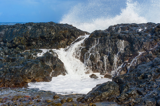 Beauty and power of the ocean as foamy water cascades over the rocks lining Hawaii's shoreline. Dynamic touch to nature, travel or adventure-themed design.