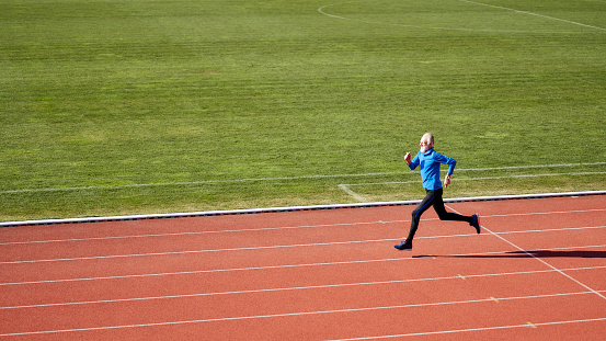 Confident senior athlete sprinting at the running track
