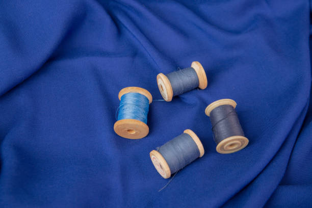 background of blue fabric and spools of blue thread. the texture of the fabric. - article textile material new imagens e fotografias de stock