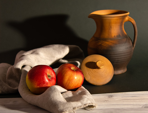 Still life in a rustic style: red apples and a pitcher.