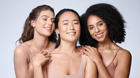 Women, faces diversity or skincare glow on studio background in healthcare wellness, self love empowerment or community support. Portrait, smile or happy beauty models or friends and makeup cosmetics