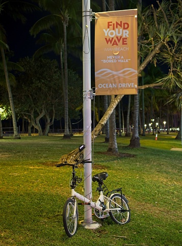 Miami Beach, FL - USA, February 1, 2023. City bicycle chained up on Miami beach sign post advertising the lifestyle along Ocean Drive.